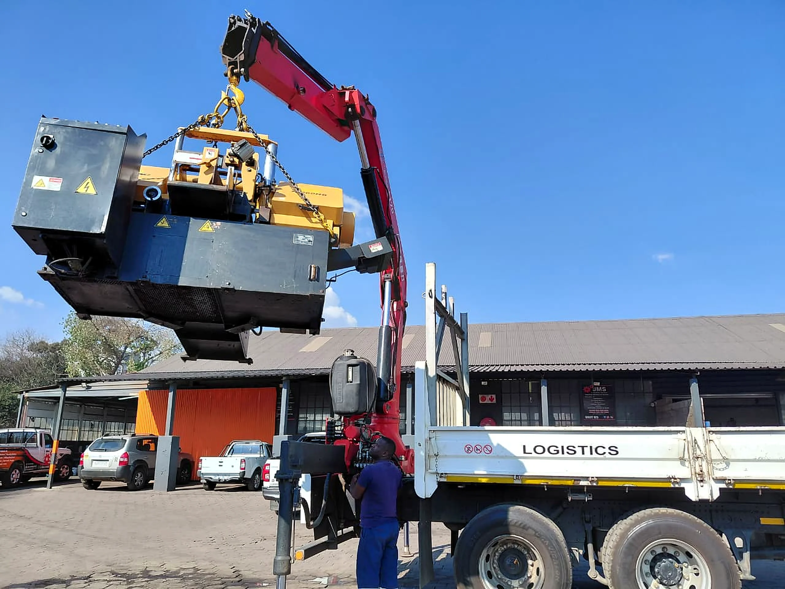 Industrial machine being lifted by truck-mounted crane