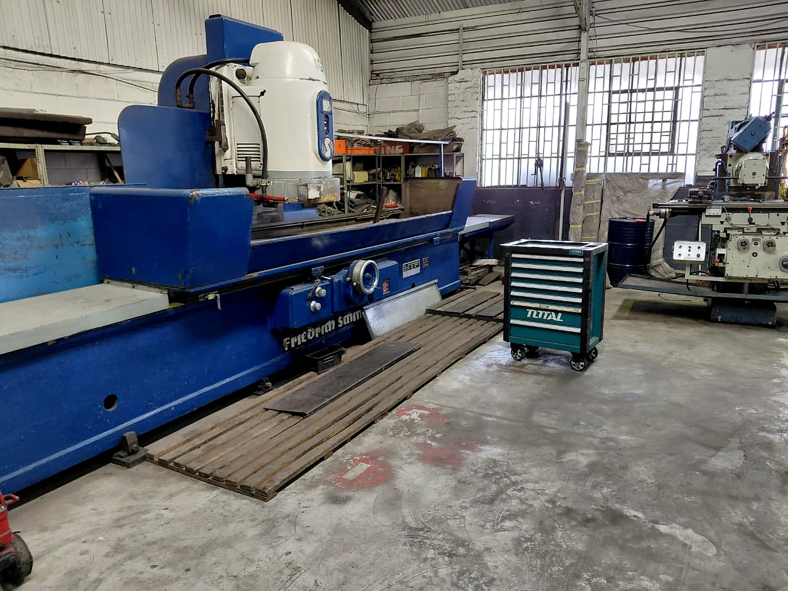 Large blue industrial grinding machine in a workshop