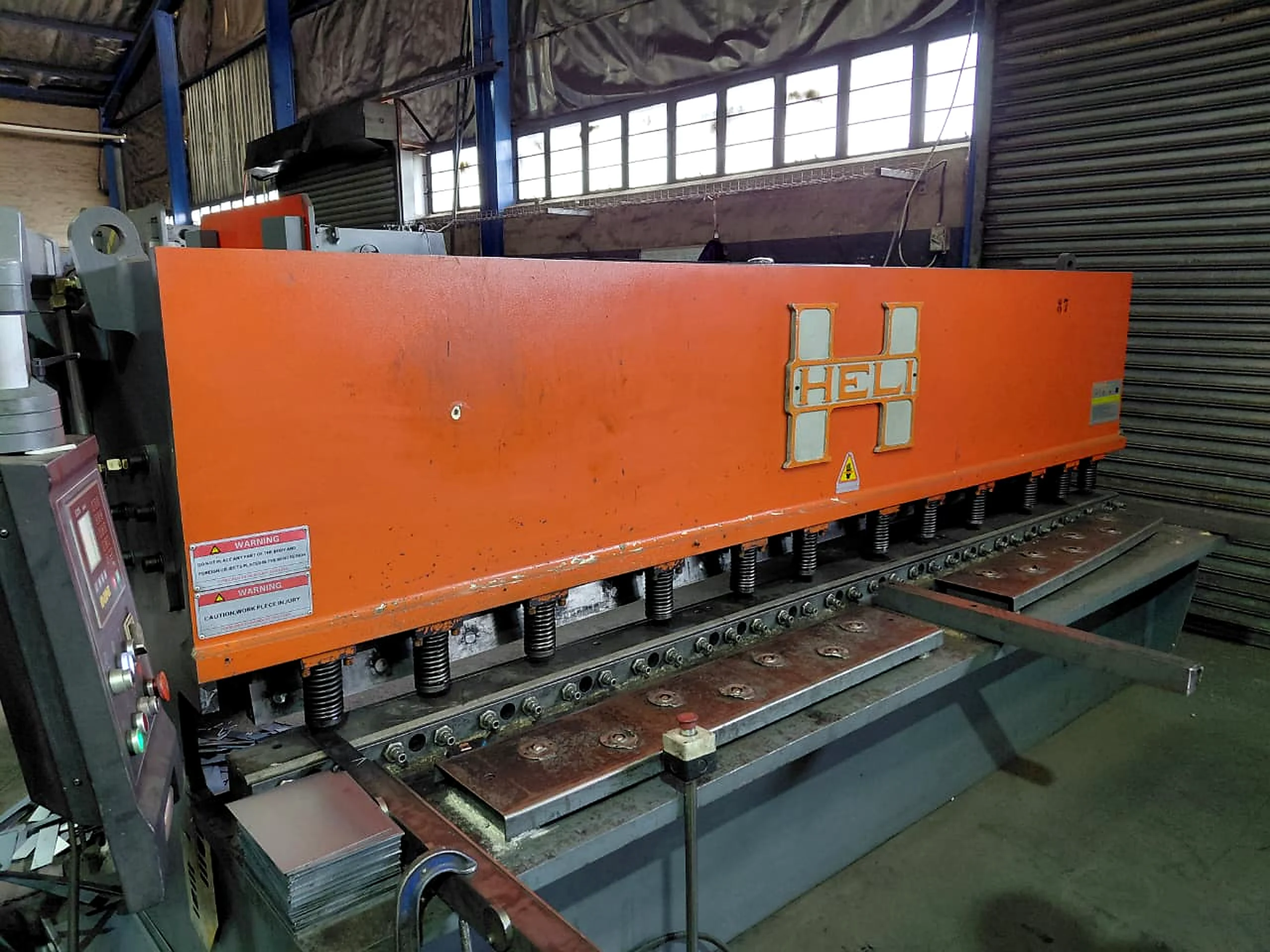 Orange industrial shear in a workshop
